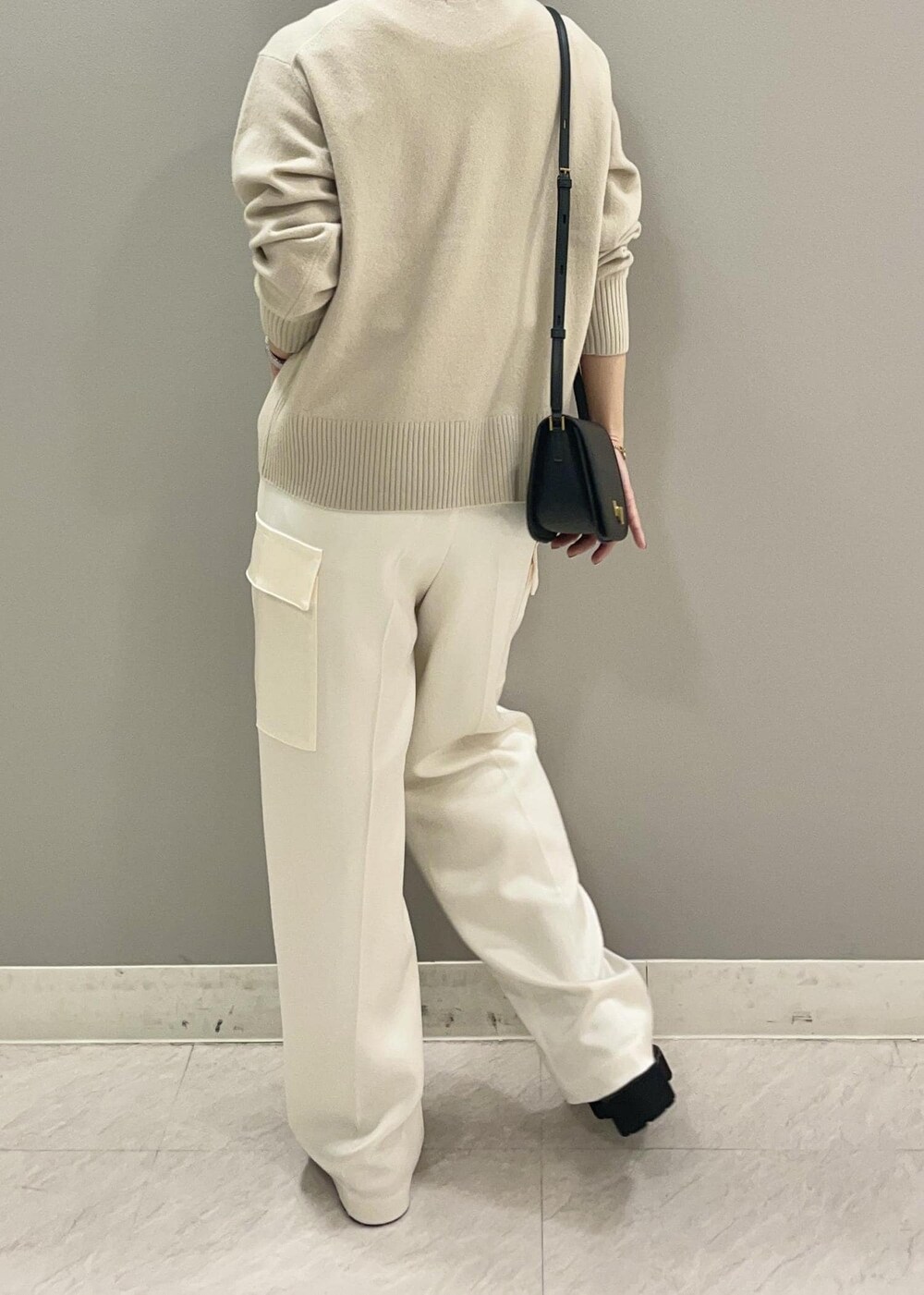 ブラック系のショルダーバッグ、ブラック系のブーツ、ベージュ系のニット/セーターを着用したレディースの秋コーディネートの5枚目の写真