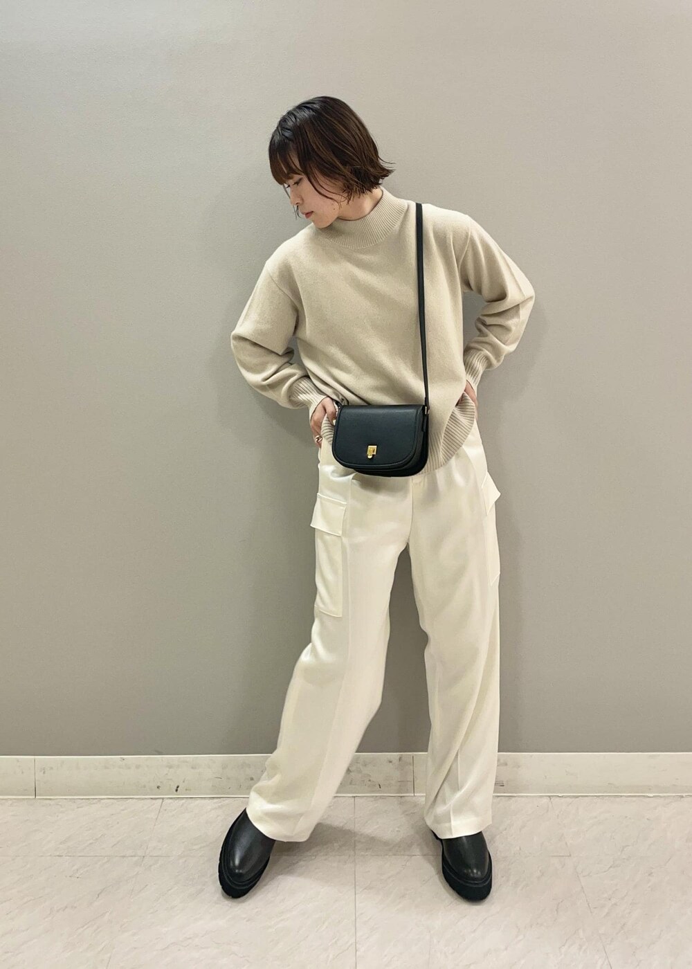 ブラック系のショルダーバッグ、ブラック系のブーツ、ベージュ系のニット/セーターを着用したレディースの秋コーディネートの2枚目の写真