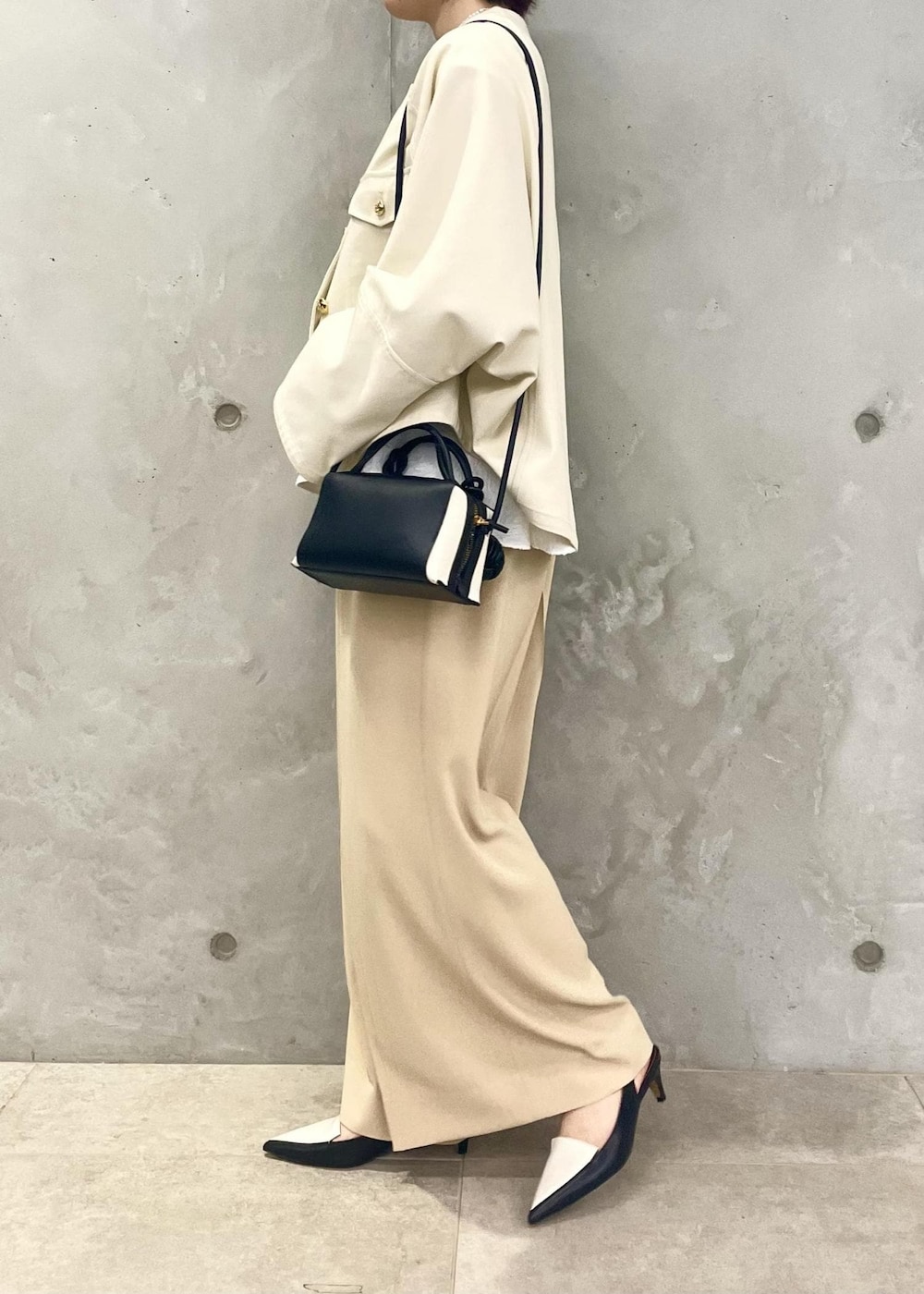 ブラック系のパンプス、ホワイト系のブルゾン、ブラック系のショルダーバッグを着用したレディースの春コーディネートの4枚目の写真