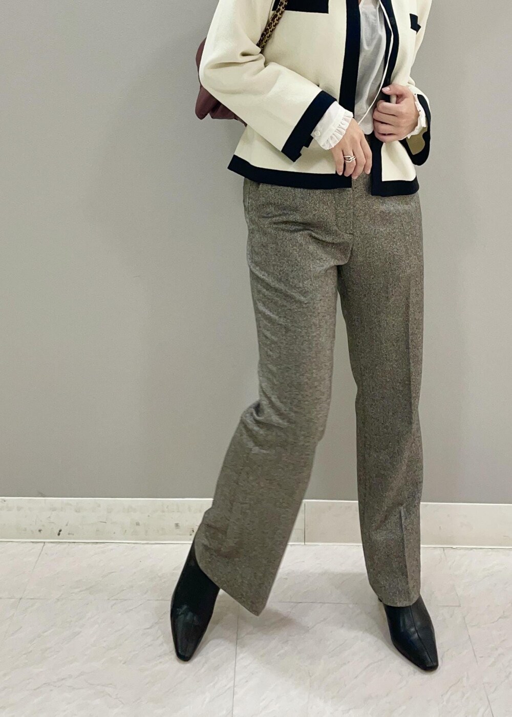 レッド系のハンドバッグ、ホワイト系のカーディガン/ボレロ、ブラック系のブーツを着用したレディースの秋コーディネートの5枚目の写真