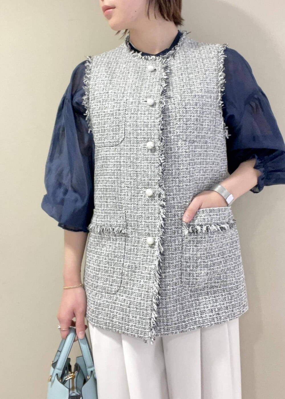 ブラック系のパンプス、ブルー系のハンドバッグ、ブラック系のベストを着用したレディースの冬コーディネートの6枚目の写真