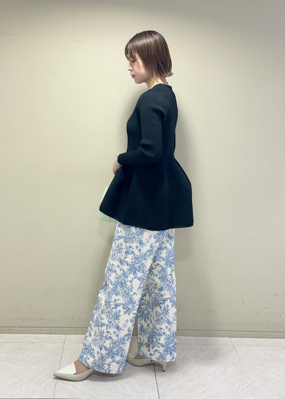 グリーン系のハンドバッグ、ブラック系のニット/セーター、ブルー系のその他パンツを着用したレディースの冬コーディネートの2枚目の写真