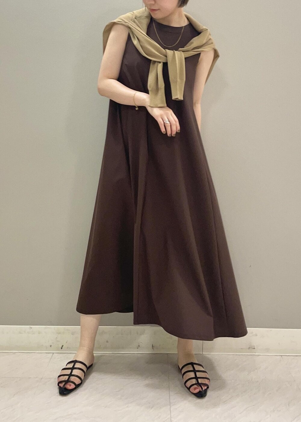 ブラック系のサンダル、ベージュ系のカーディガン/ボレロ、ブラウン系のワンピースを着用したレディースの夏コーディネートの2枚目の写真