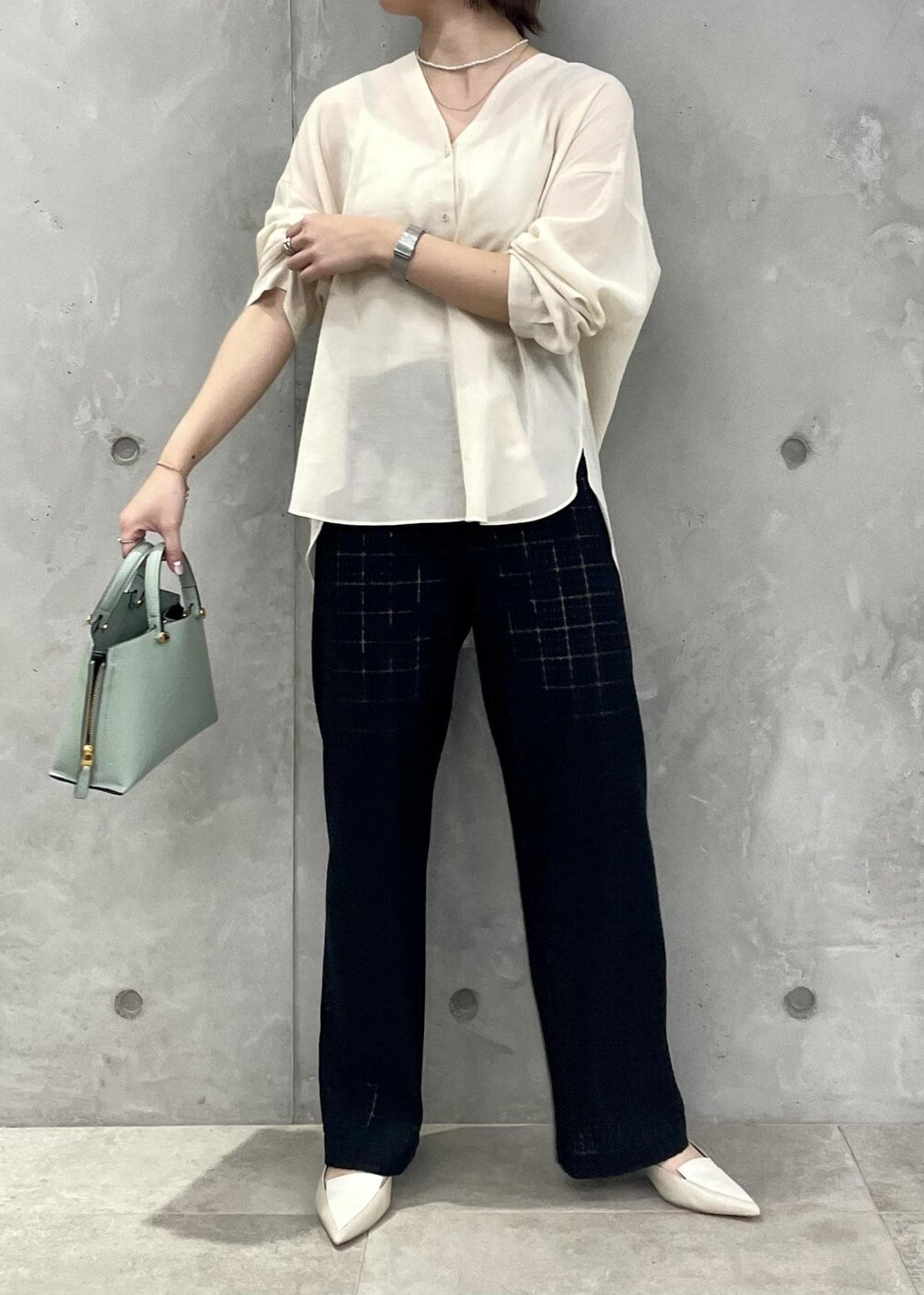 グリーン系のハンドバッグ、ベージュ系のパンプス、ブラック系のその他パンツを着用したレディースの春コーディネートの2枚目の写真