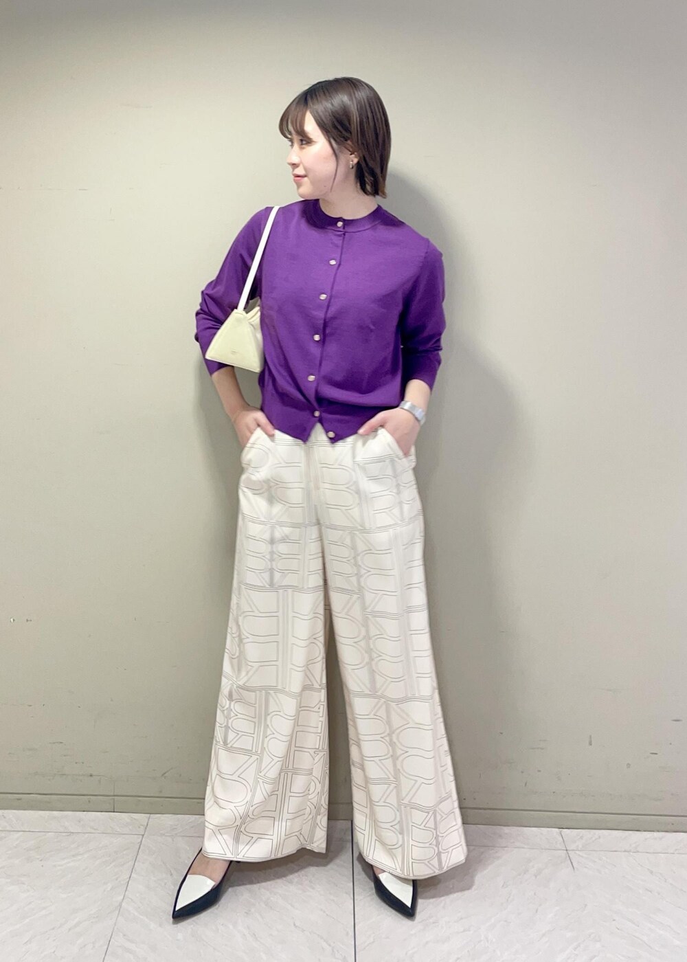 ベージュ系のハンドバッグ、ホワイト系のその他パンツ、パープル系のカーディガン/ボレロを着用したレディースの冬コーディネートの2枚目の写真