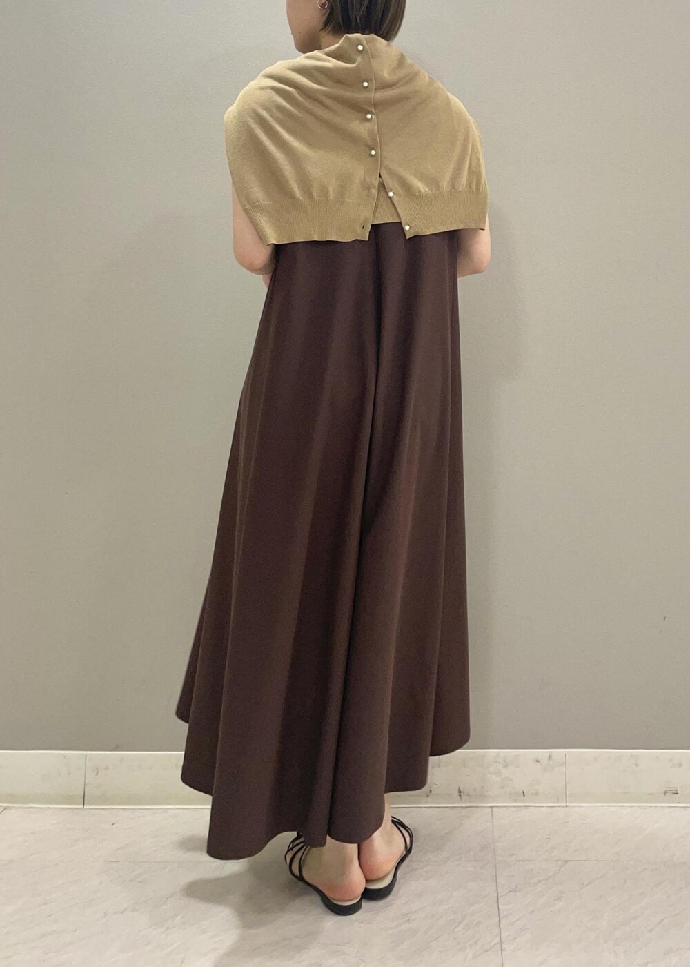 ブラック系のサンダル、ベージュ系のカーディガン/ボレロ、ブラウン系のワンピースを着用したレディースの夏コーディネートの3枚目の写真