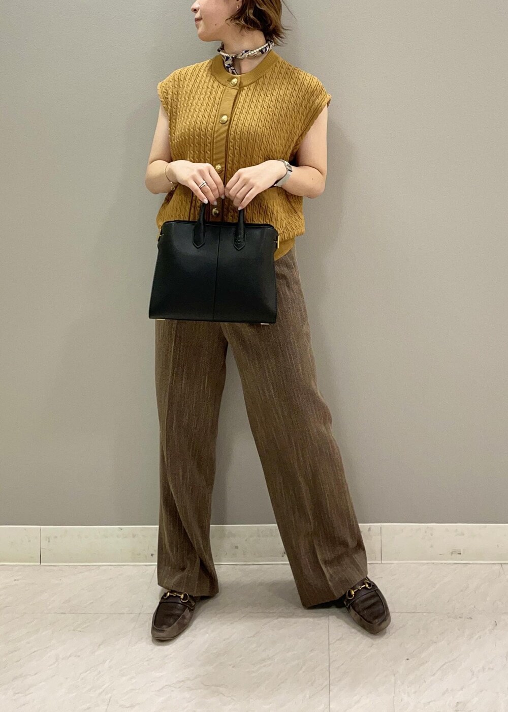 イエロー系のベスト、ブラック系のトートバッグ、ブラウン系のその他パンツを着用したレディースの夏コーディネートの4枚目の写真