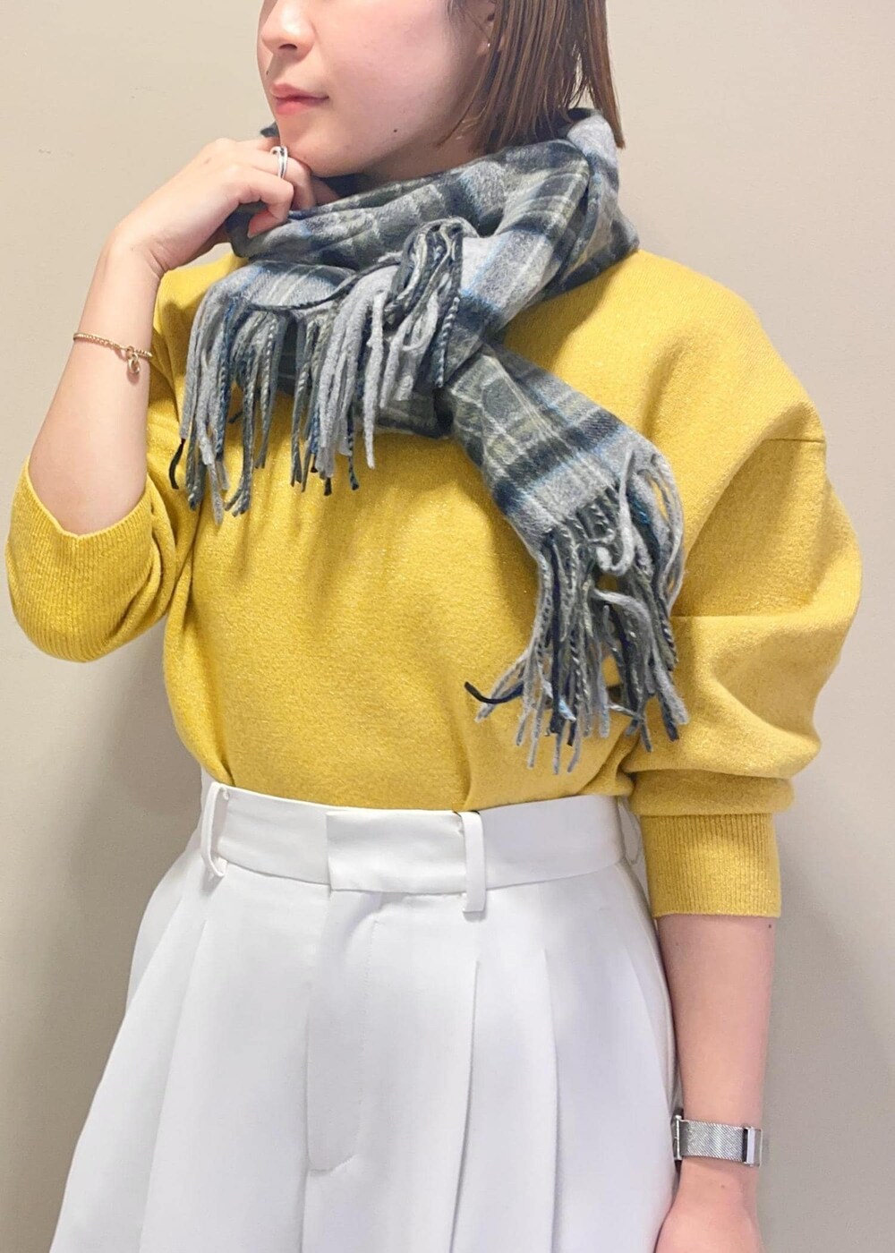 ベージュ系のハンドバッグ、ブラック系のブーツ、イエロー系のニット/セーターを着用したレディースの冬コーディネートの6枚目の写真