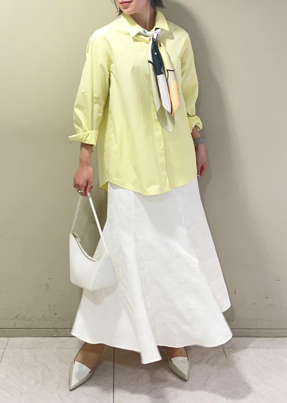 ベージュ系のハンドバッグ、イエロー系のシャツ/ブラウス、ベージュ系のパンプスを着用したレディースの春コーディネートの2枚目の写真