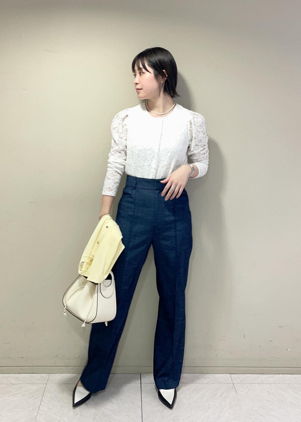 ブラック系のパンプス、イエロー系のカーディガン/ボレロ、ホワイト系のTシャツ/カットソーを着用したレディースの春コーディネートの2枚目の写真