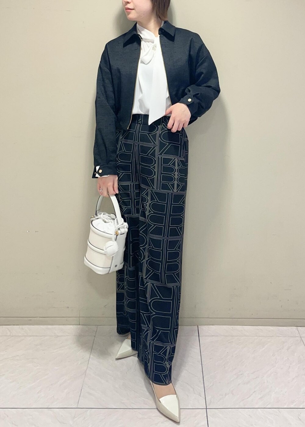 ホワイト系のハンドバッグ、ブラック系のその他パンツ、ブラック系のブルゾンを着用したレディースの冬コーディネートの3枚目の写真