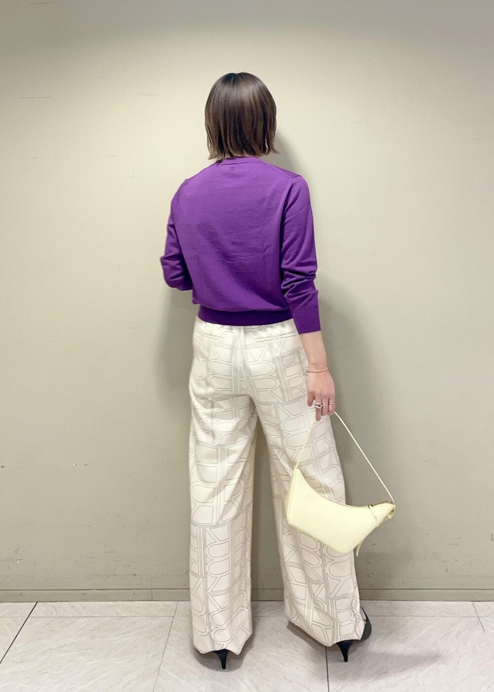 ベージュ系のハンドバッグ、ホワイト系のその他パンツ、パープル系のカーディガン/ボレロを着用したレディースの冬コーディネートの4枚目の写真