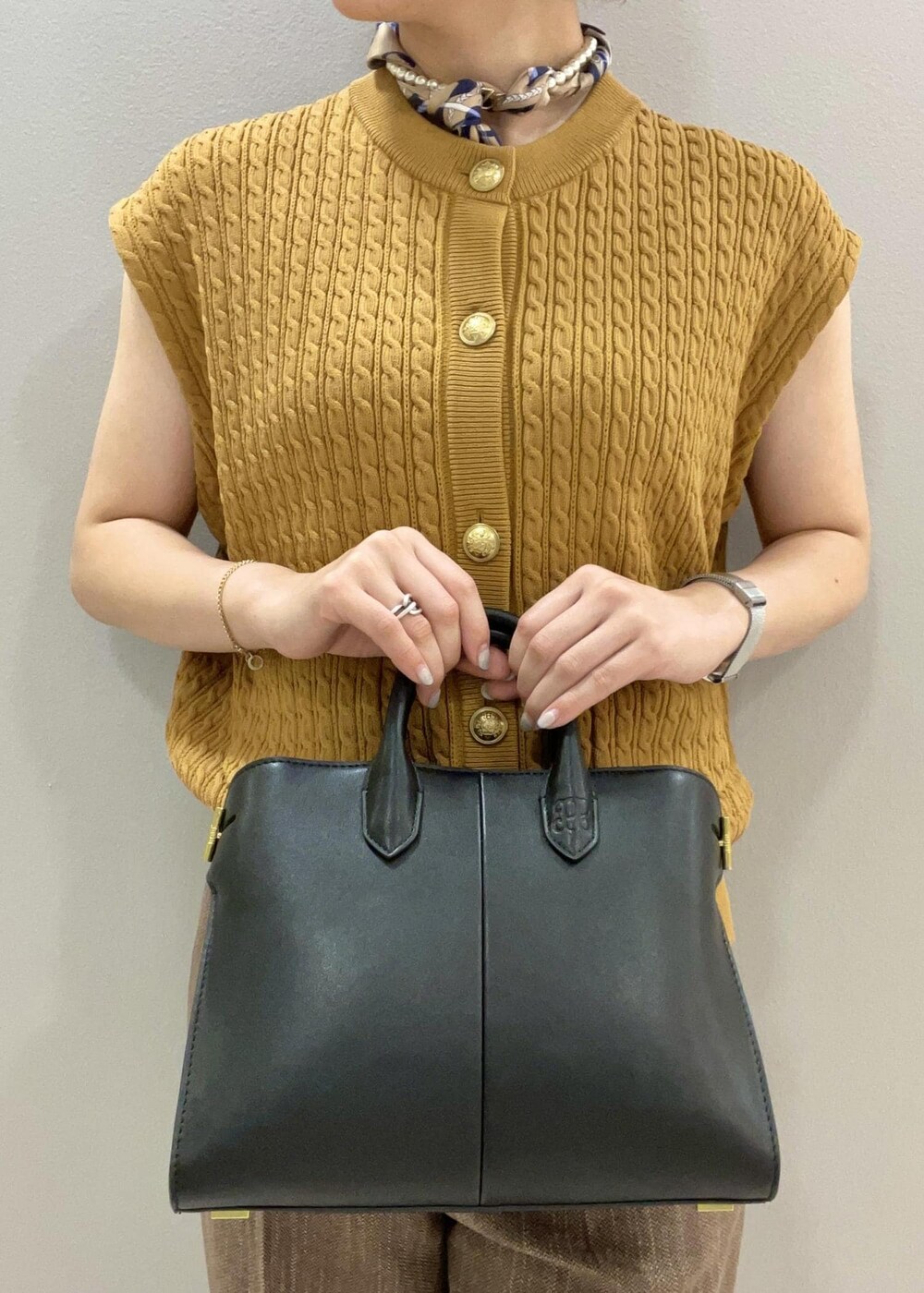 イエロー系のベスト、ブラック系のトートバッグ、ブラウン系のその他パンツを着用したレディースの夏コーディネートの9枚目の写真