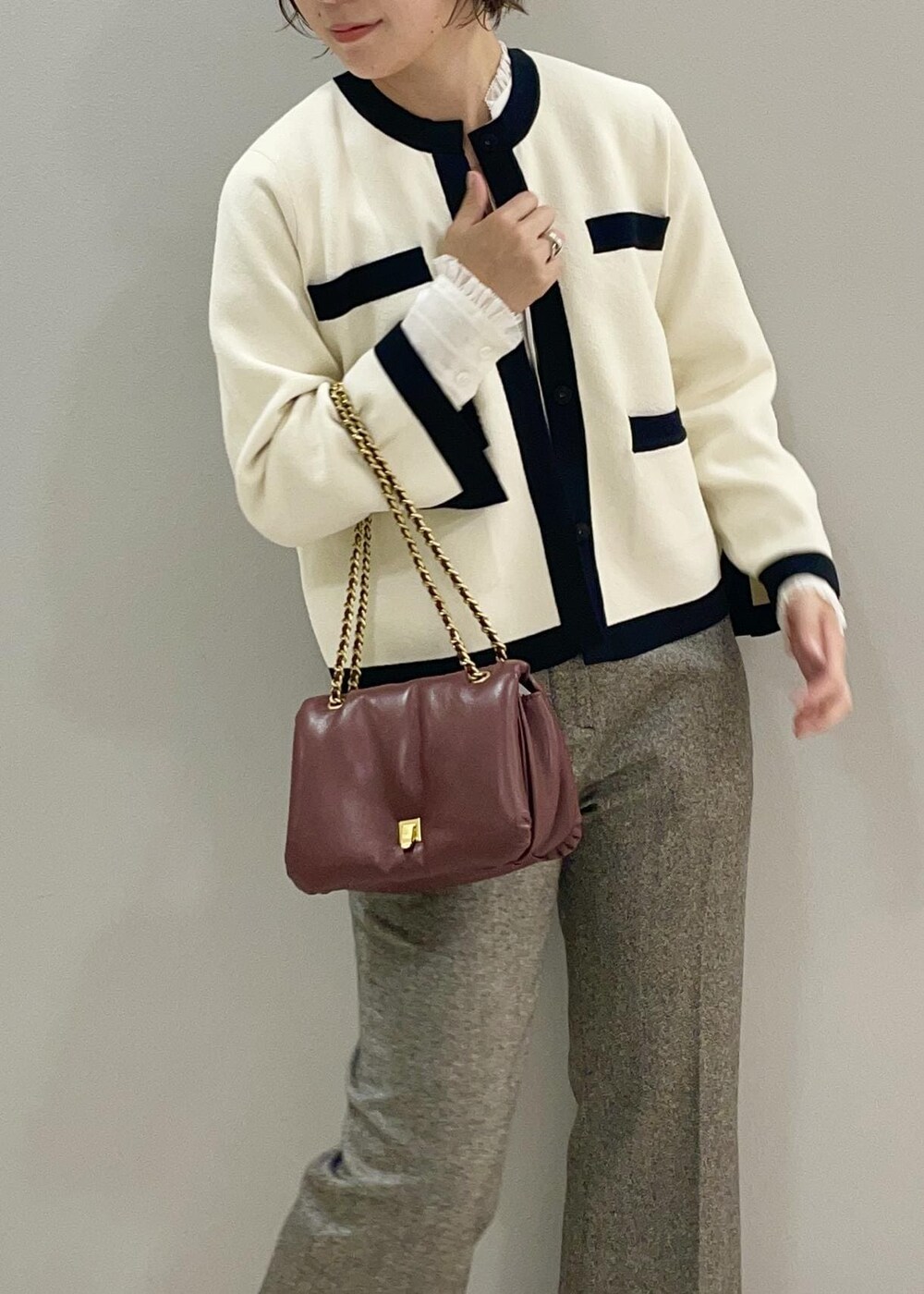 レッド系のハンドバッグ、ホワイト系のカーディガン/ボレロ、ブラック系のブーツを着用したレディースの秋コーディネートの6枚目の写真