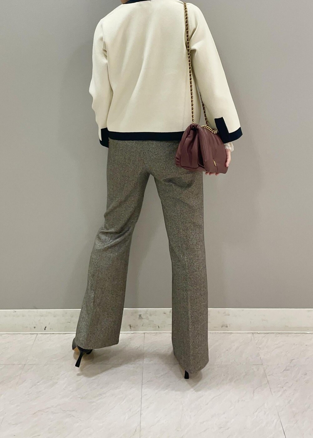 レッド系のハンドバッグ、ホワイト系のカーディガン/ボレロ、ブラック系のブーツを着用したレディースの秋コーディネートの4枚目の写真