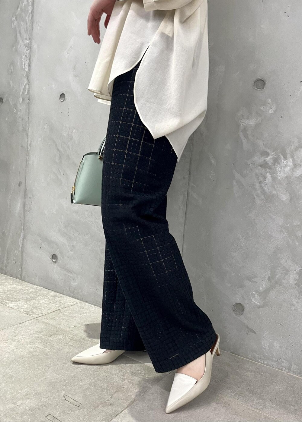 グリーン系のハンドバッグ、ベージュ系のパンプス、ブラック系のその他パンツを着用したレディースの春コーディネートの10枚目の写真