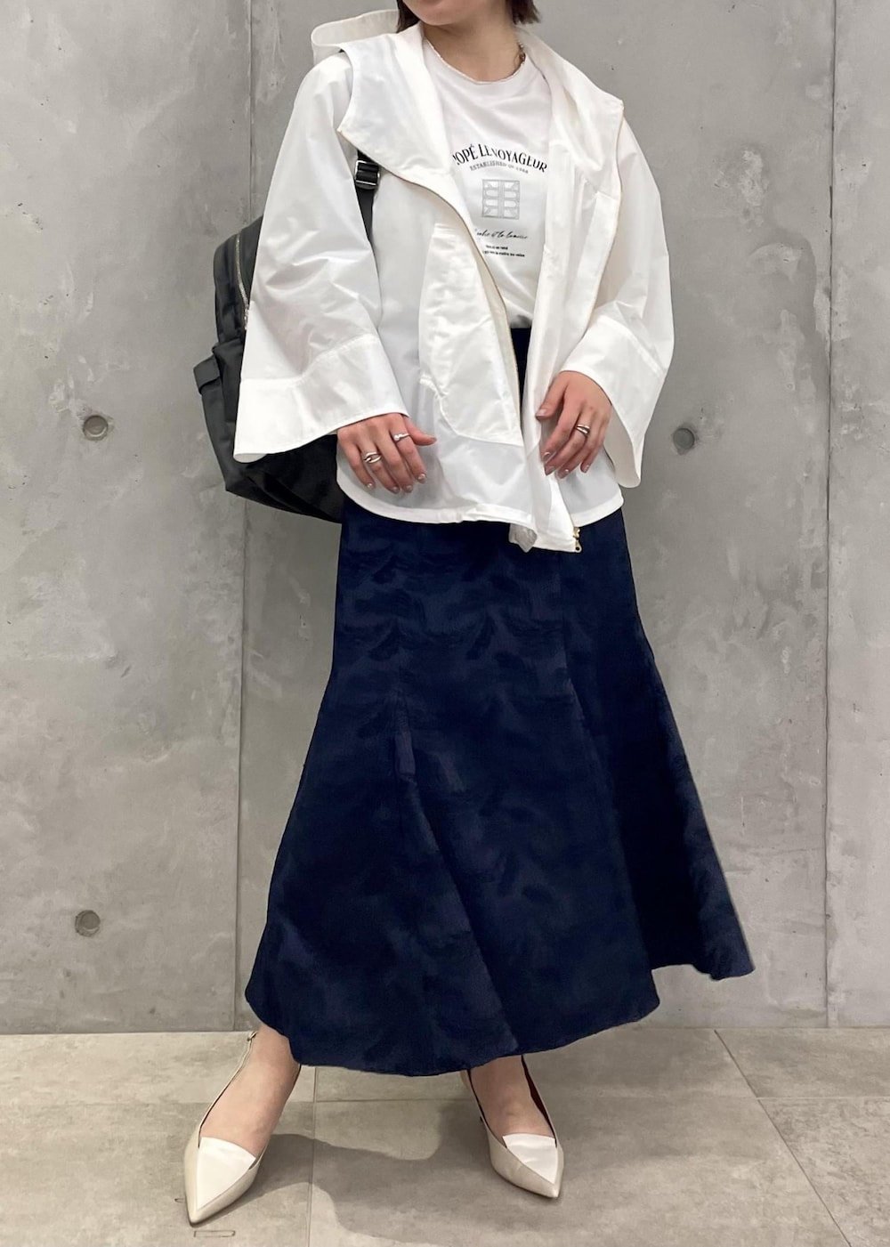 ベージュ系のパンプス、ブルー系のスカート、ホワイト系のマウンテンパーカーを着用したレディースの春コーディネートの3枚目の写真