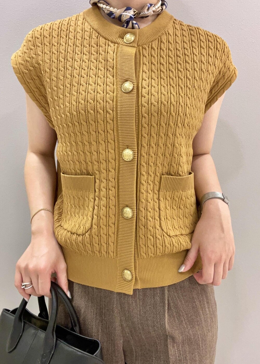 イエロー系のベスト、ブラック系のトートバッグ、ブラウン系のその他パンツを着用したレディースの夏コーディネートの6枚目の写真