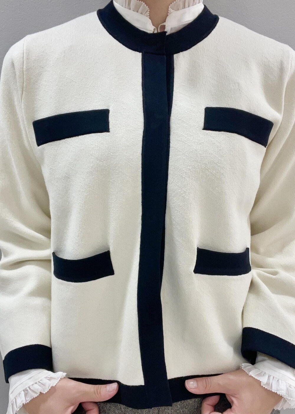 レッド系のハンドバッグ、ホワイト系のカーディガン/ボレロ、ブラック系のブーツを着用したレディースの秋コーディネートの8枚目の写真