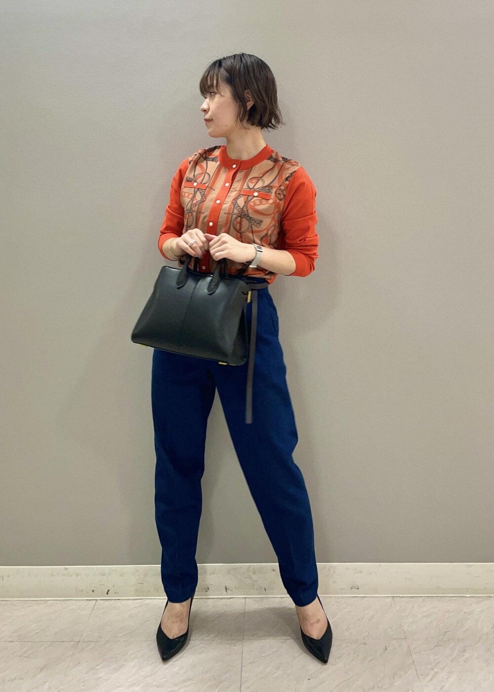 オレンジ系のカーディガン/ボレロ、ブルー系のデニムパンツ、ブラック系のパンプスを着用したレディースの夏コーディネートの2枚目の写真