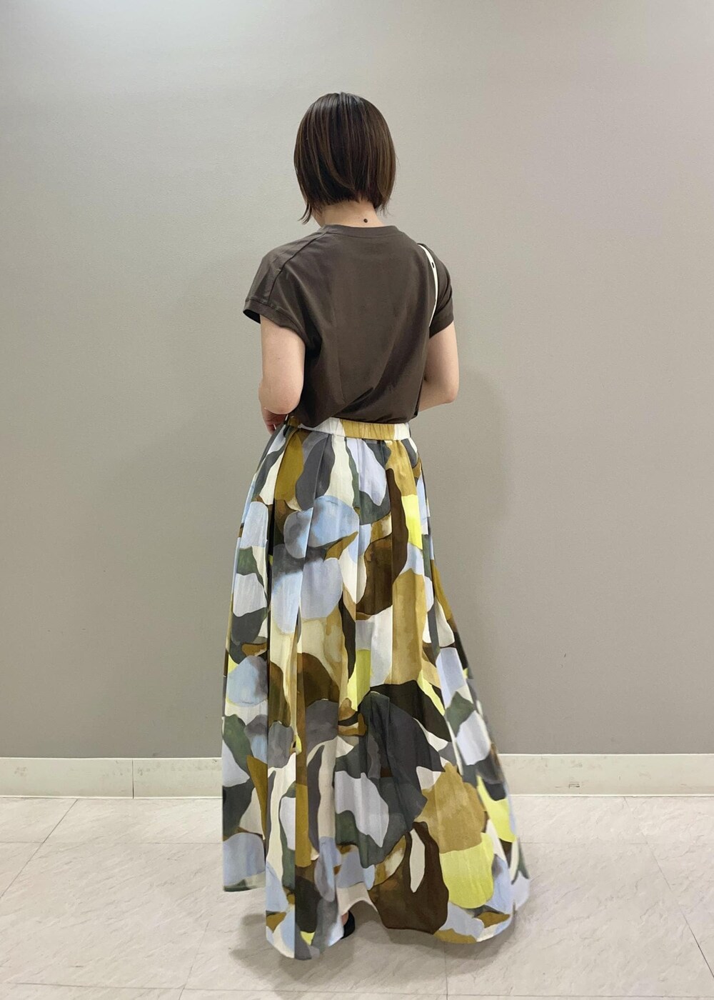 ホワイト系のハンドバッグ、グリーン系のTシャツ/カットソー、ブルー系のスカートを着用したレディースの夏コーディネートの3枚目の写真