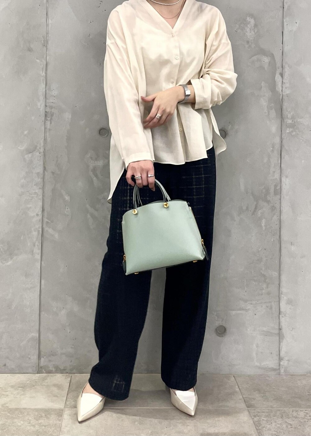 グリーン系のハンドバッグ、ベージュ系のパンプス、ブラック系のその他パンツを着用したレディースの春コーディネートの4枚目の写真