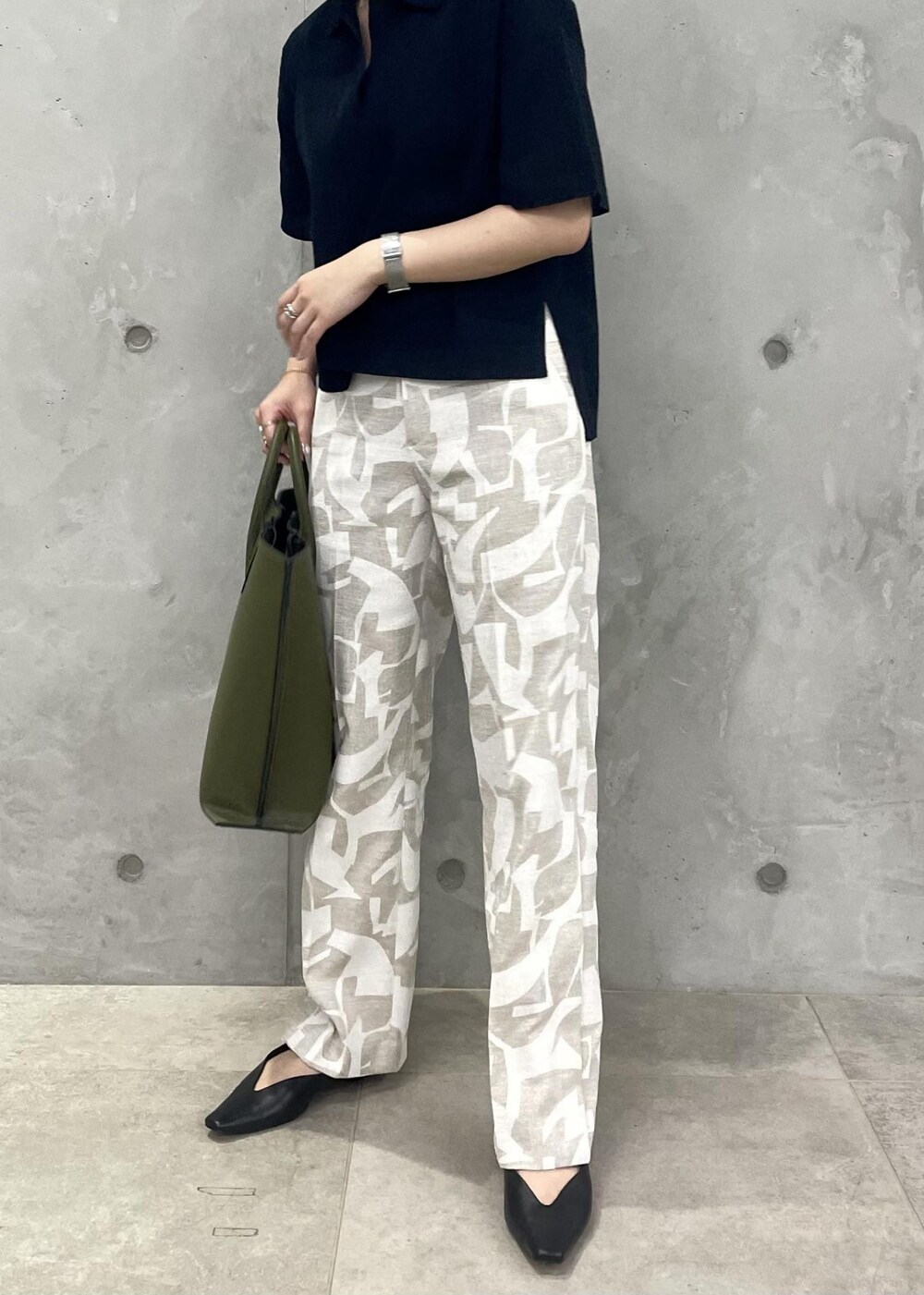 グリーン系のトートバッグ、ブラック系のパンプス、ブルー系のニット/セーターを着用したレディースの春コーディネートの4枚目の写真