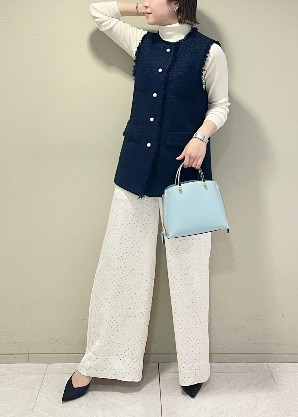ブラック系のパンプス、ブルー系のハンドバッグ、ホワイト系のニット/セーターを着用したレディースの冬コーディネートの4枚目の写真