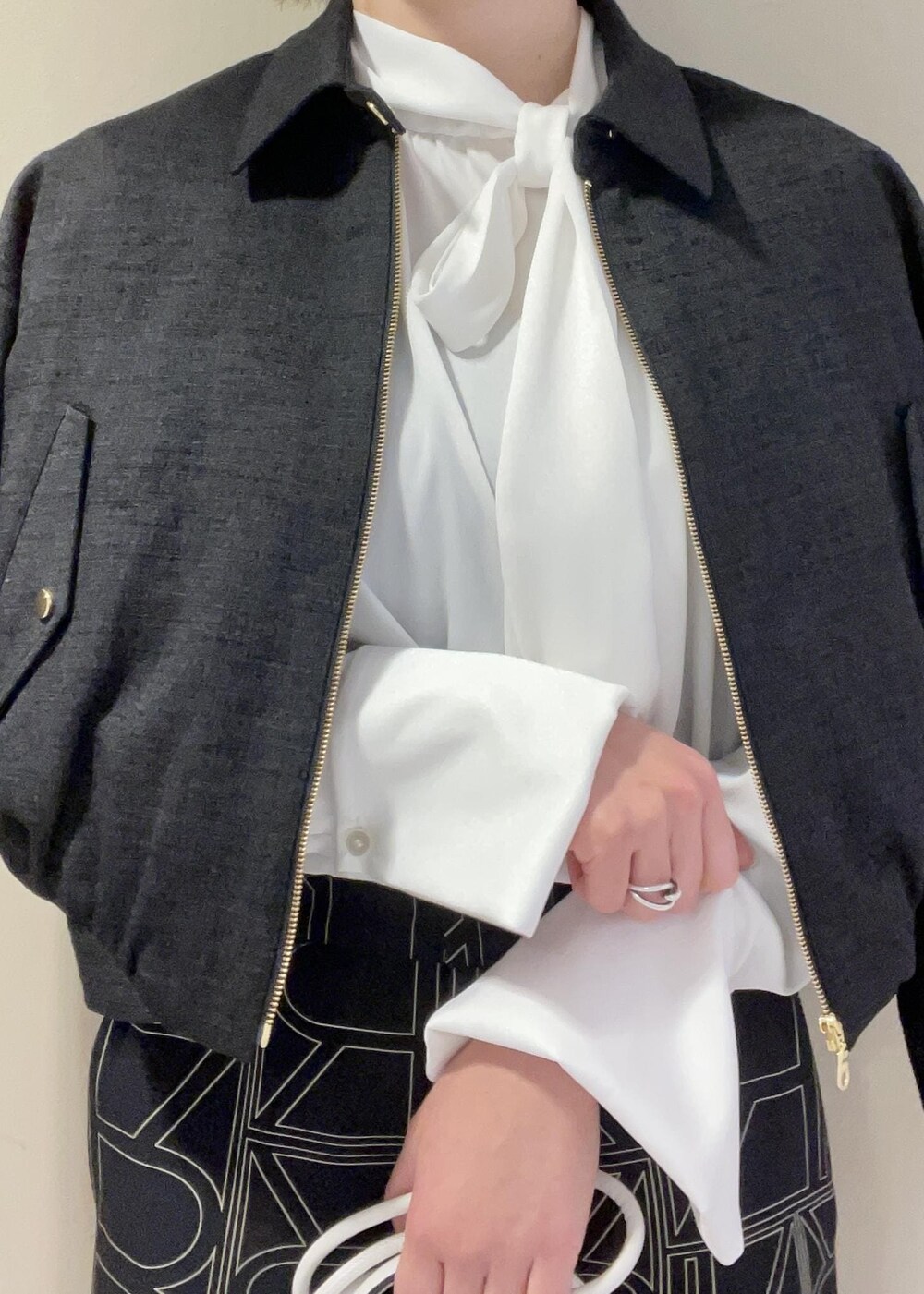 ホワイト系のハンドバッグ、ブラック系のその他パンツ、ブラック系のブルゾンを着用したレディースの冬コーディネートの6枚目の写真