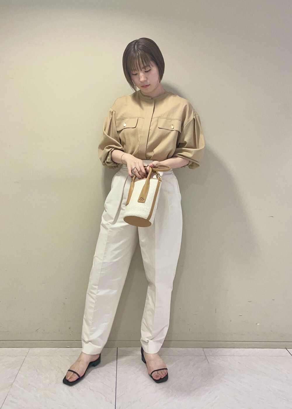 ブラック系のサンダル、ベージュ系のハンドバッグ、ホワイト系のその他パンツを着用したレディースの夏コーディネートの2枚目の写真