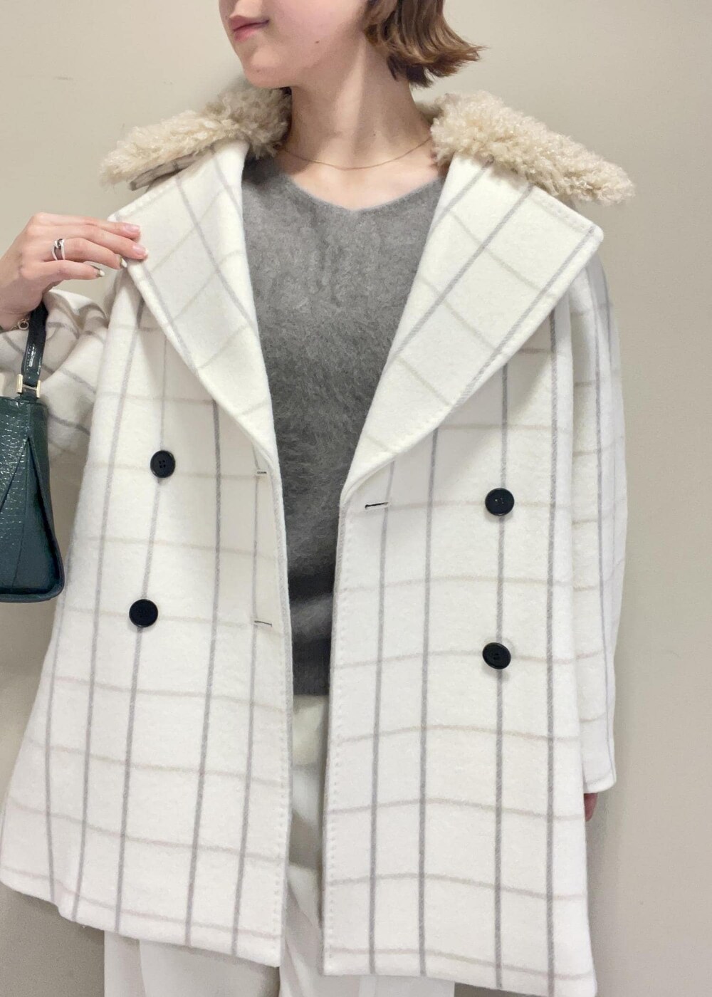 ホワイト系のチェスターコート、グリーン系のショルダーバッグ、ブラウン系のニット/セーターを着用したレディースの秋コーディネートの9枚目の写真