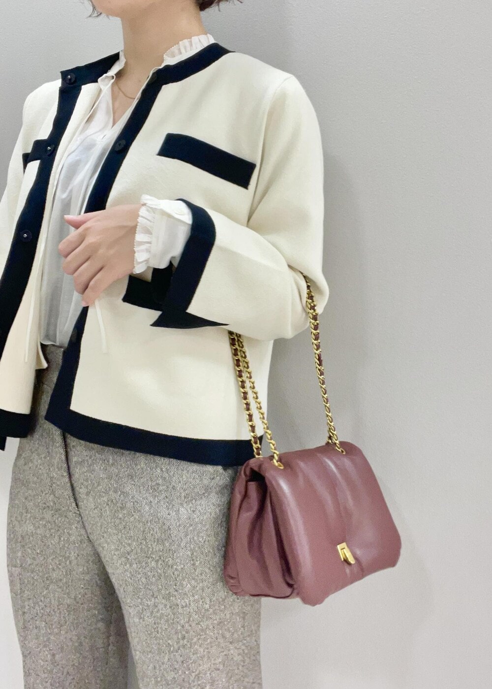 レッド系のハンドバッグ、ホワイト系のカーディガン/ボレロ、ブラック系のブーツを着用したレディースの秋コーディネートの7枚目の写真