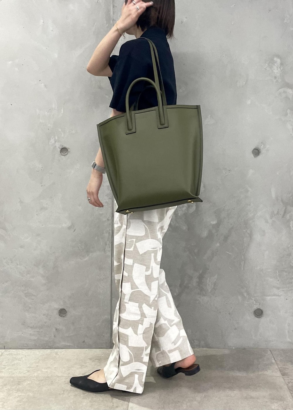 グリーン系のトートバッグ、ブラック系のパンプス、ブルー系のニット/セーターを着用したレディースの春コーディネートの5枚目の写真