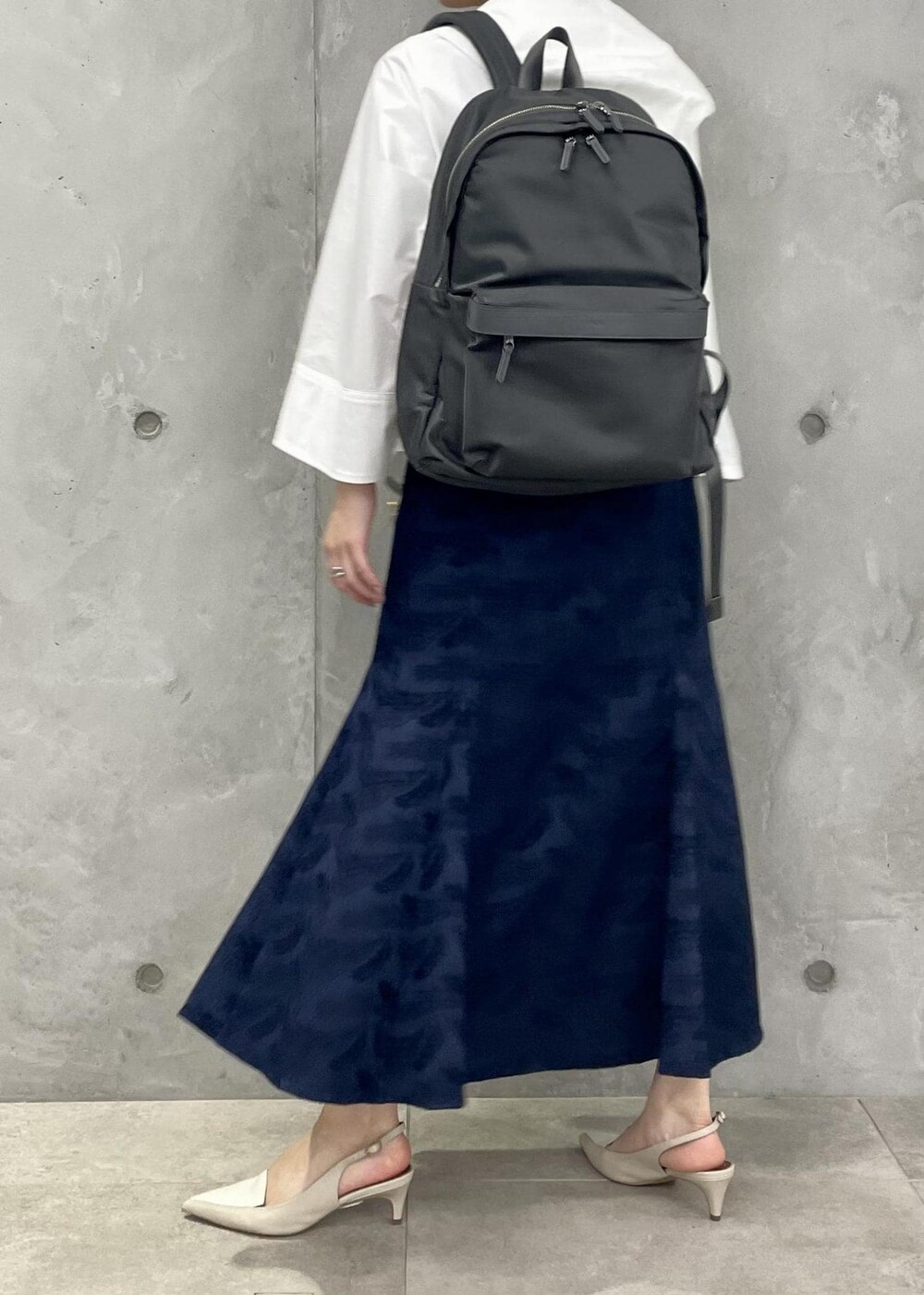 ベージュ系のパンプス、ブルー系のスカート、ホワイト系のマウンテンパーカーを着用したレディースの春コーディネートの4枚目の写真