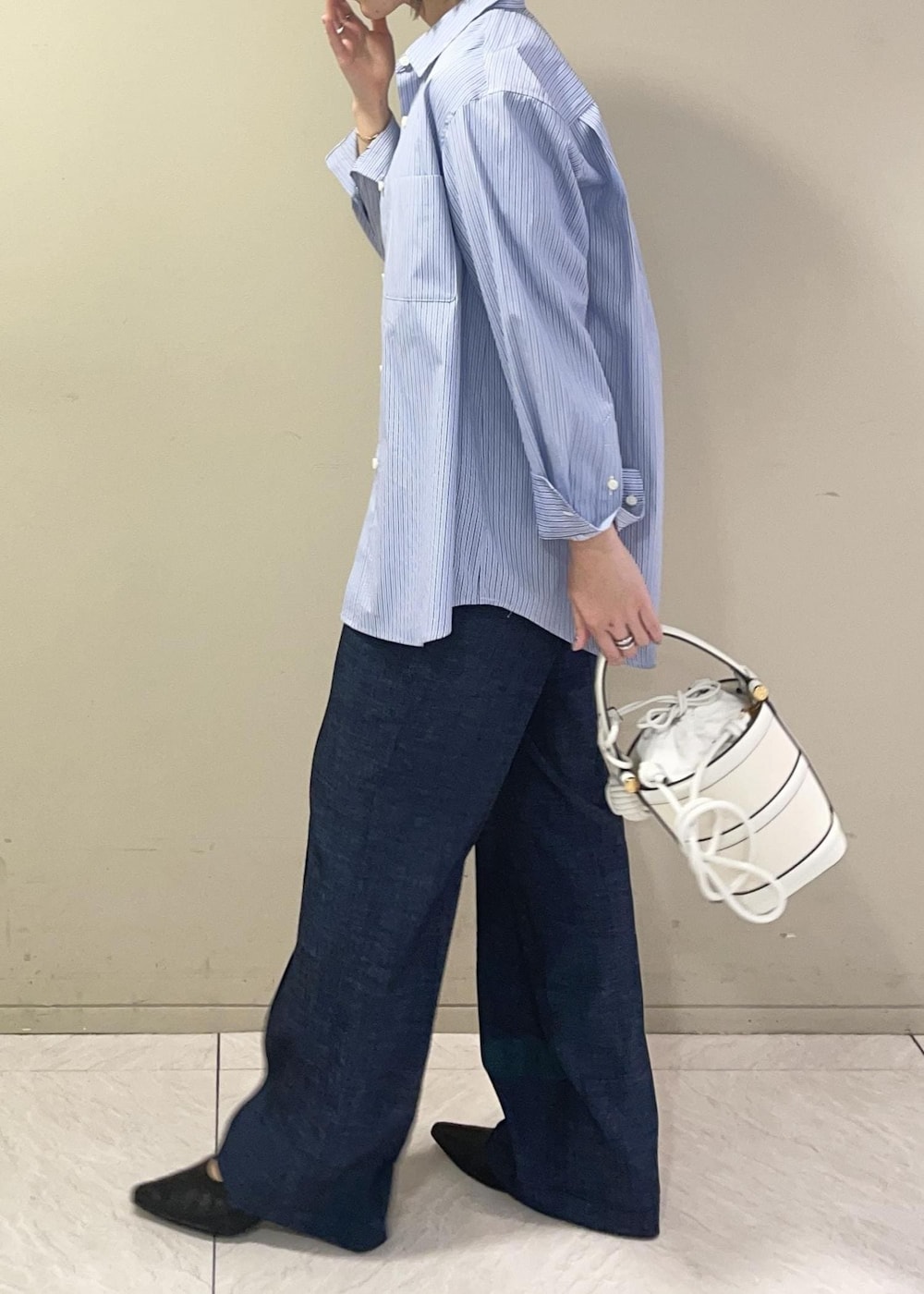 ホワイト系のハンドバッグ、ブルー系のデニムパンツ、ブルー系のシャツ/ブラウスを着用したレディースの春コーディネートの5枚目の写真