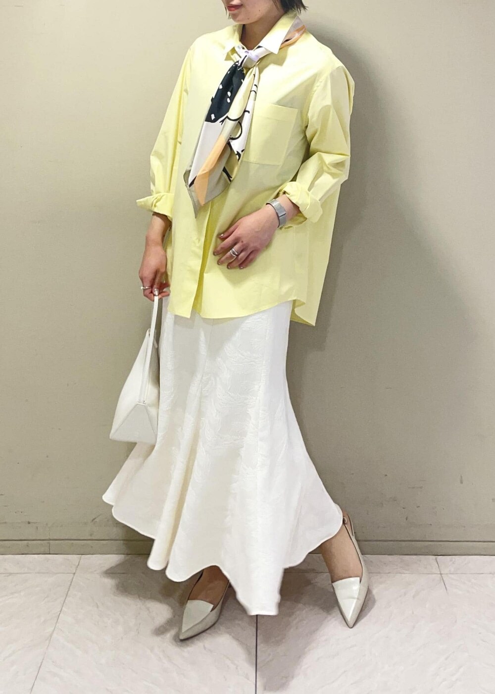 ベージュ系のハンドバッグ、イエロー系のシャツ/ブラウス、ベージュ系のパンプスを着用したレディースの春コーディネートの3枚目の写真