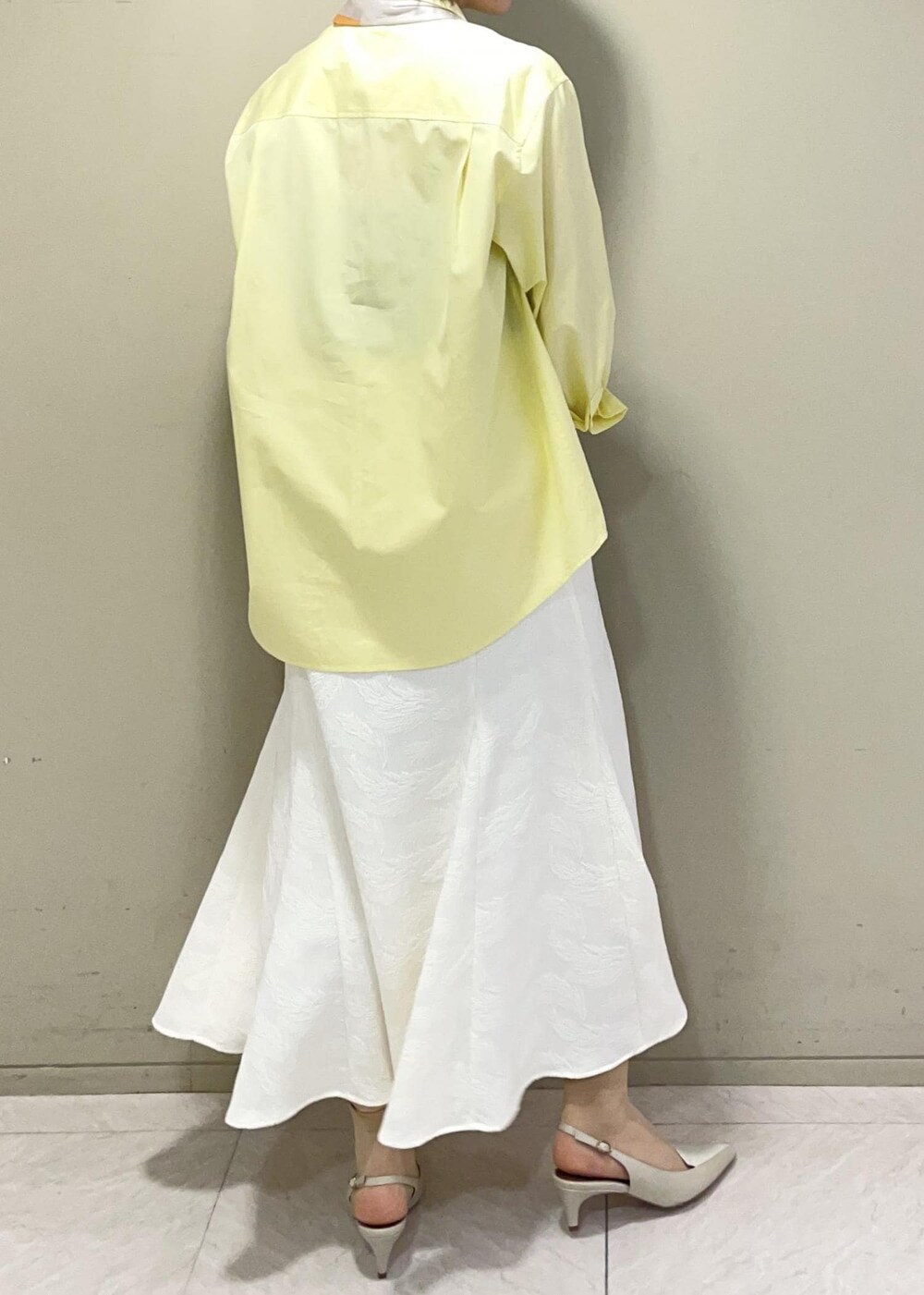 ベージュ系のハンドバッグ、イエロー系のシャツ/ブラウス、ベージュ系のパンプスを着用したレディースの春コーディネートの6枚目の写真