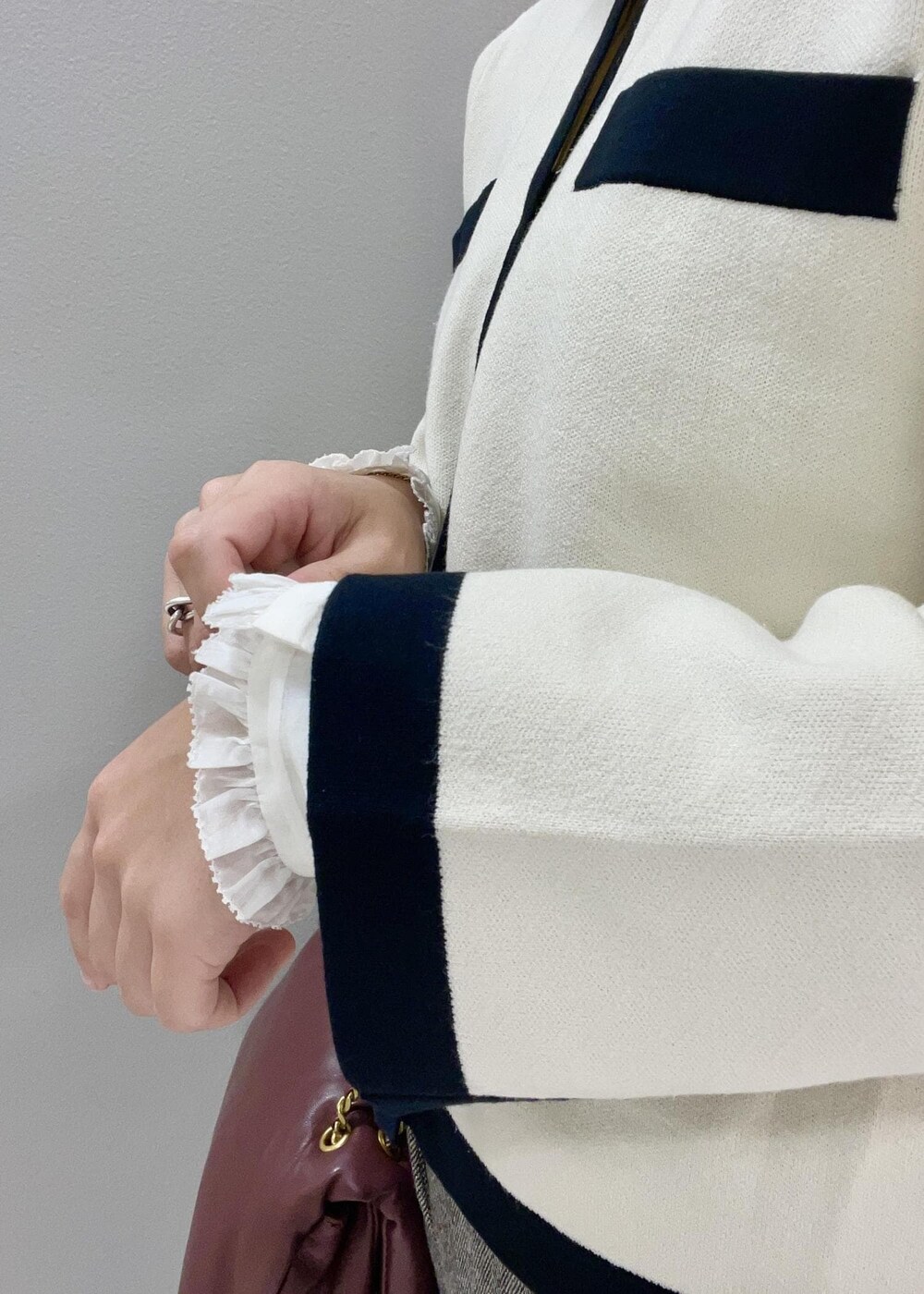 レッド系のハンドバッグ、ホワイト系のカーディガン/ボレロ、ブラック系のブーツを着用したレディースの秋コーディネートの9枚目の写真