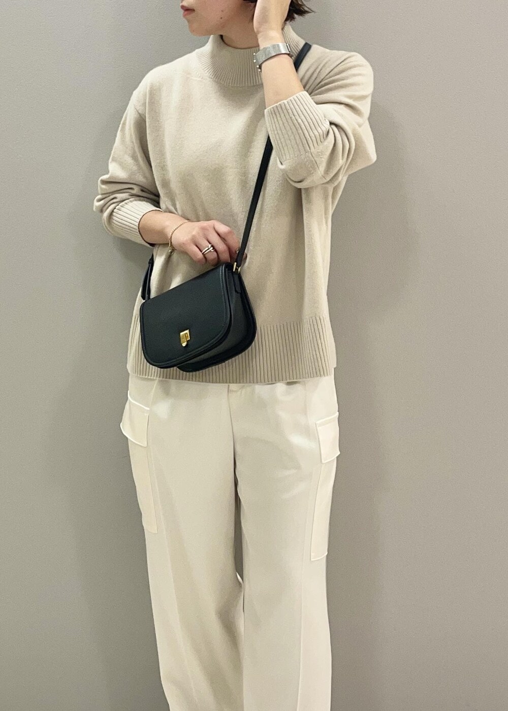 ブラック系のショルダーバッグ、ブラック系のブーツ、ベージュ系のニット/セーターを着用したレディースの秋コーディネートの7枚目の写真