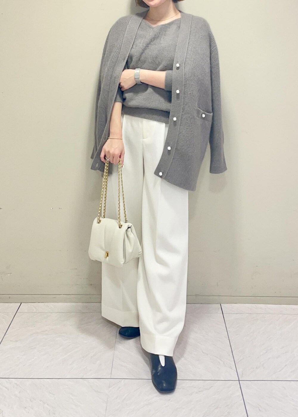 ホワイト系のハンドバッグ、ブラウン系のカーディガン/ボレロ、ブラウン系のニット/セーターを着用したレディースの秋コーディネートの2枚目の写真