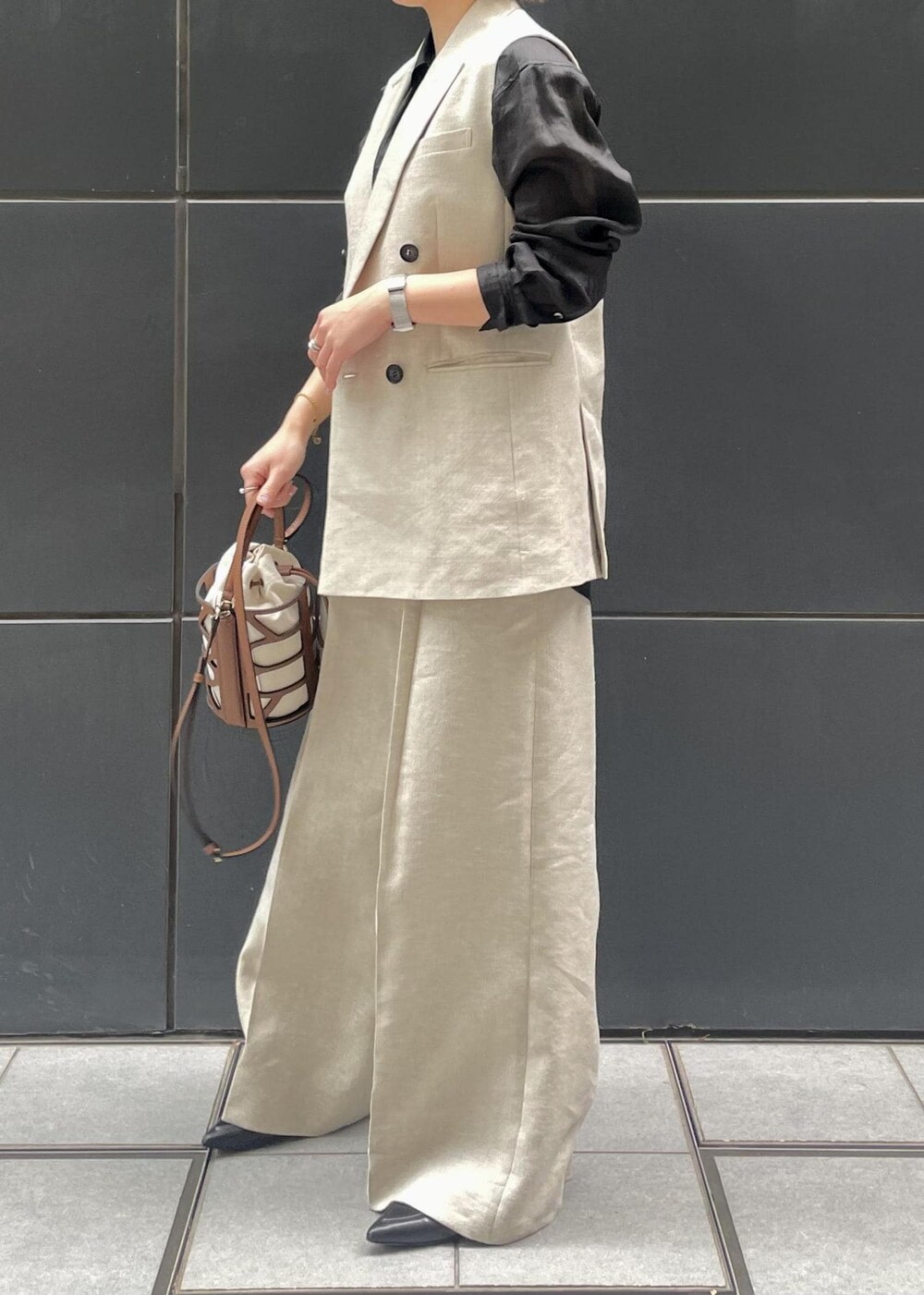 ブラック系のパンプス、ブラック系のシャツ/ブラウス、ベージュ系のベストを着用したレディースの春コーディネートの2枚目の写真