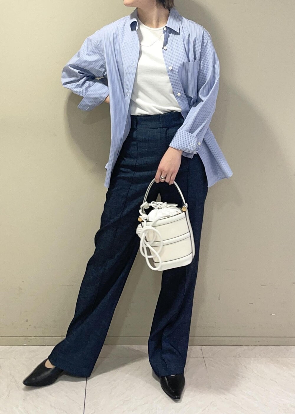 ホワイト系のハンドバッグ、ブルー系のデニムパンツ、ブルー系のシャツ/ブラウスを着用したレディースの春コーディネートの3枚目の写真