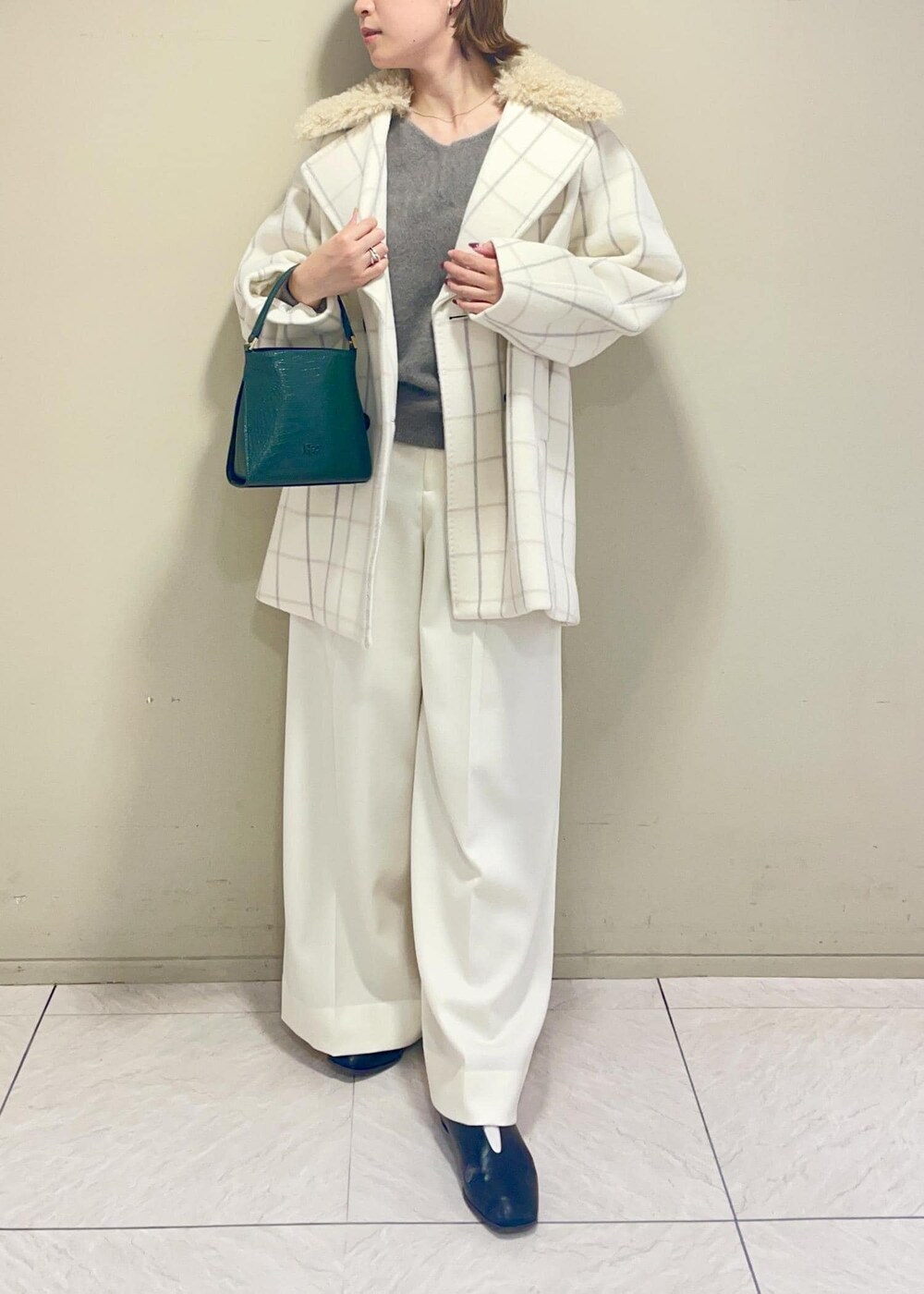ホワイト系のチェスターコート、グリーン系のショルダーバッグ、ブラウン系のニット/セーターを着用したレディースの秋コーディネートの2枚目の写真