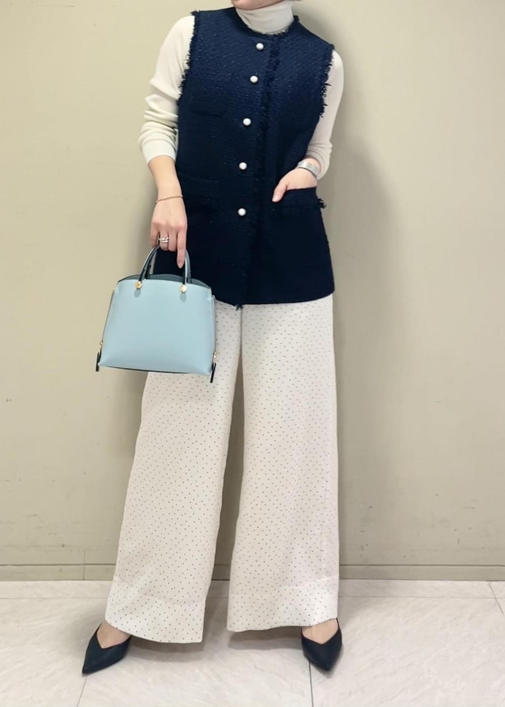 ブラック系のパンプス、ブルー系のハンドバッグ、ホワイト系のニット/セーターを着用したレディースの冬コーディネートの6枚目の写真