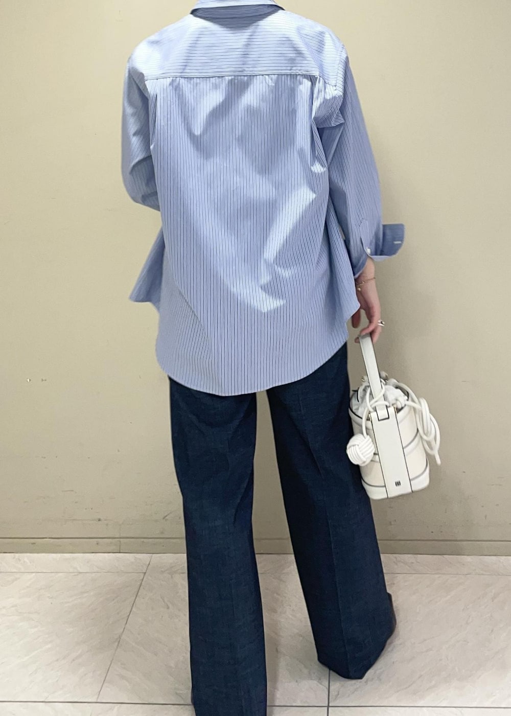 ホワイト系のハンドバッグ、ブルー系のデニムパンツ、ブルー系のシャツ/ブラウスを着用したレディースの春コーディネートの6枚目の写真