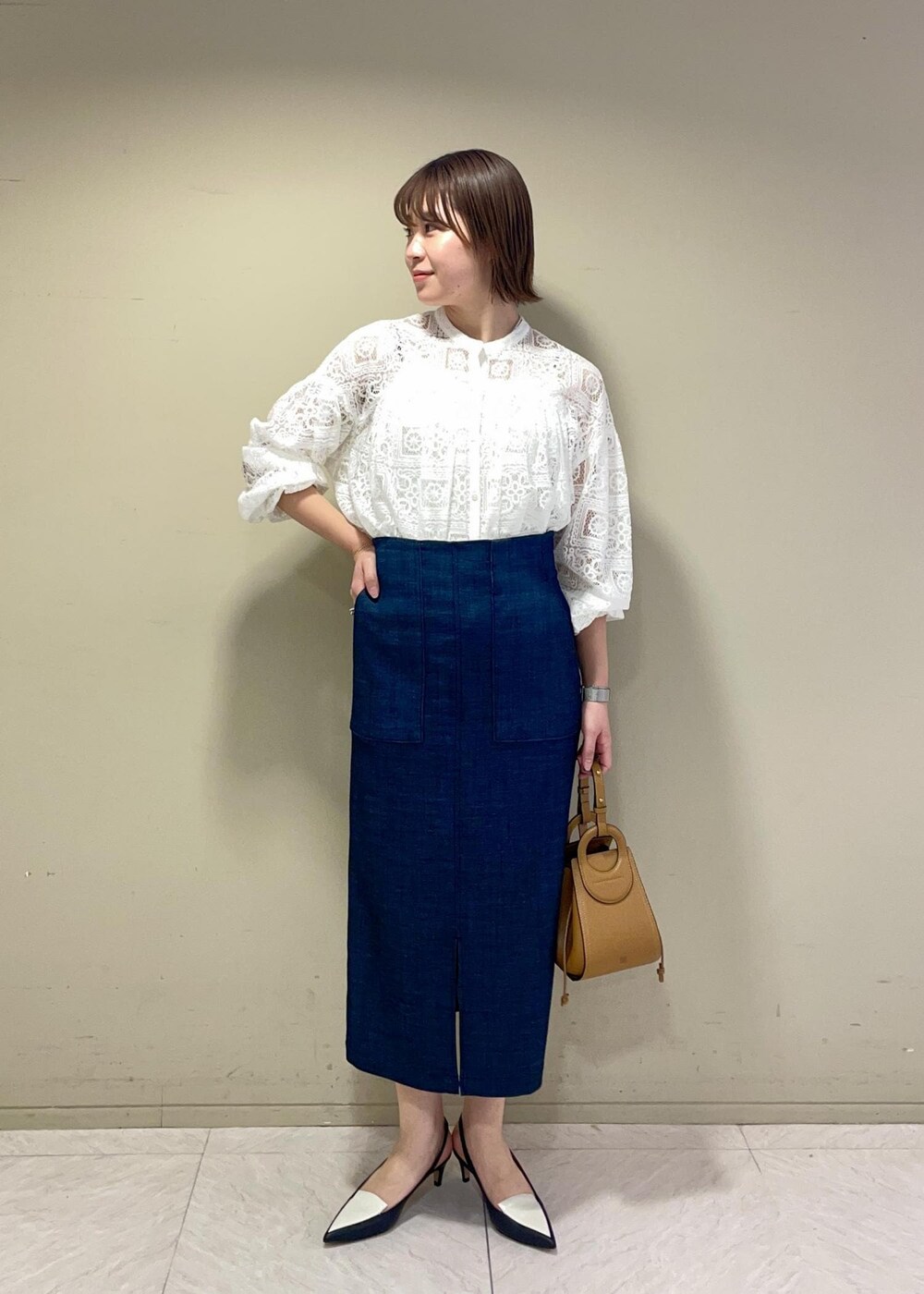 イエロー系のショルダーバッグ、ブルー系のスカート、ブラック系のパンプスを着用したレディースの冬コーディネートの3枚目の写真