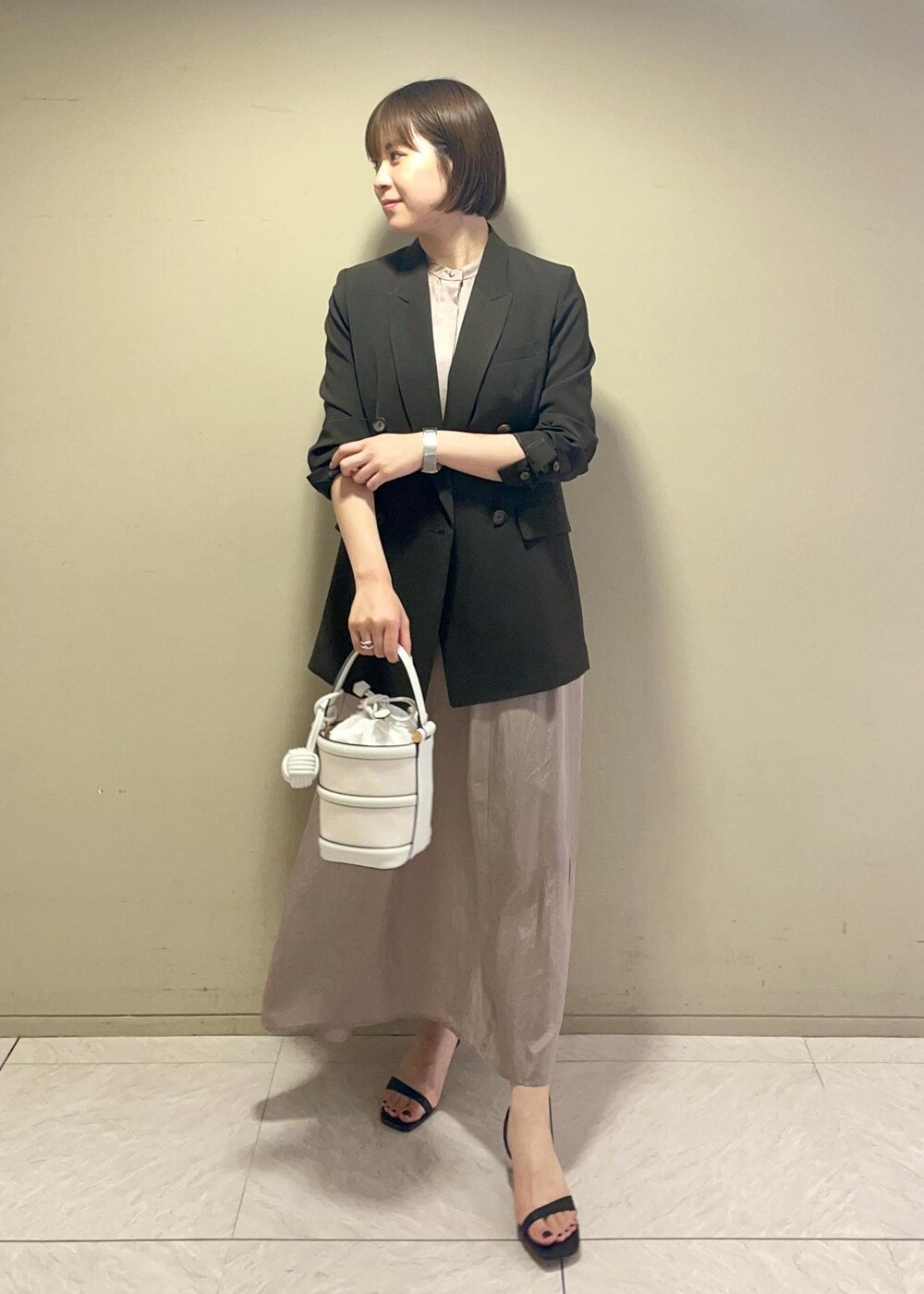 ホワイト系のハンドバッグ、ブラック系のサンダル、ブラウン系のテーラードジャケットを着用したレディースの春コーディネートの2枚目の写真