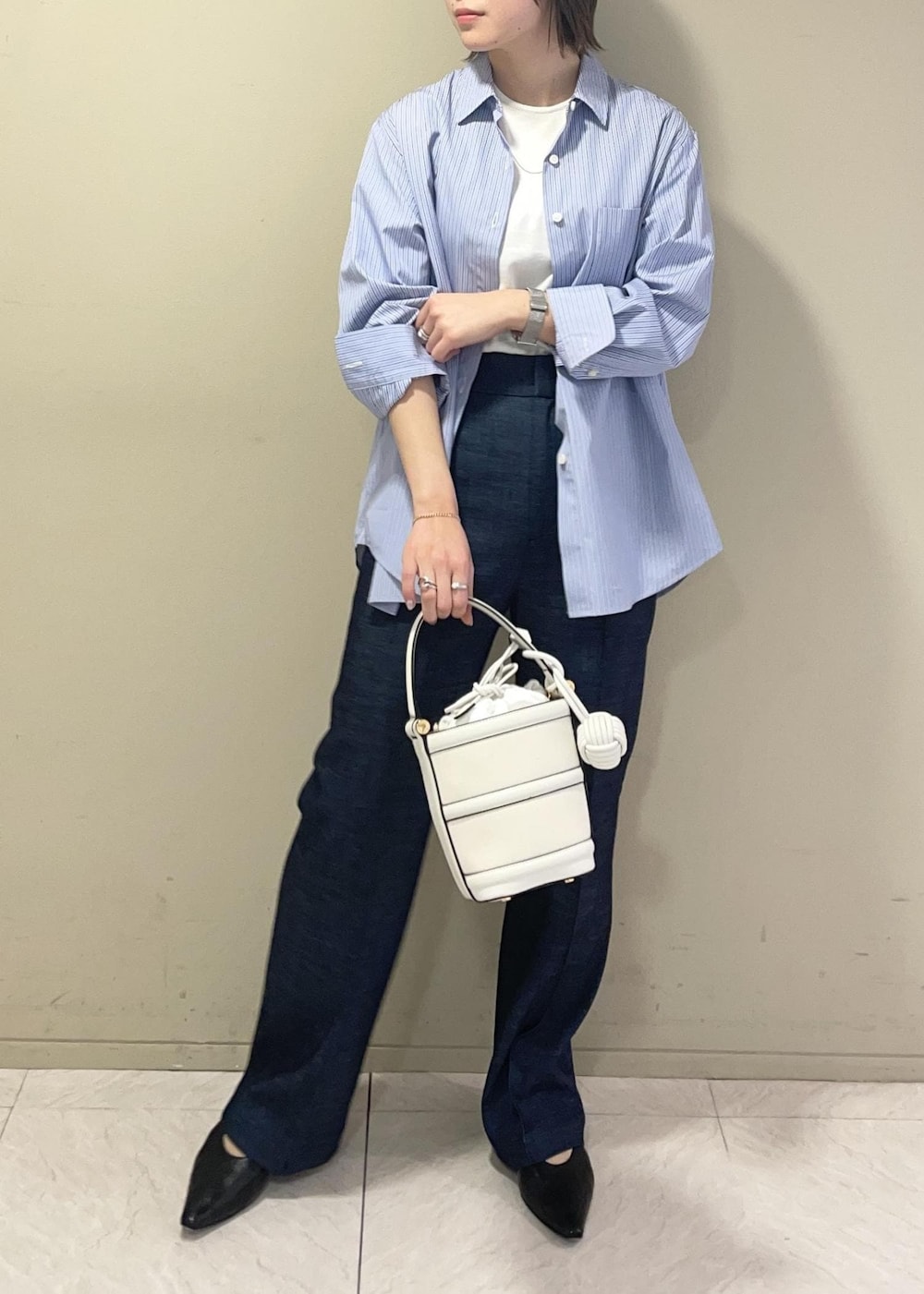 ホワイト系のハンドバッグ、ブルー系のデニムパンツ、ブルー系のシャツ/ブラウスを着用したレディースの春コーディネートの2枚目の写真