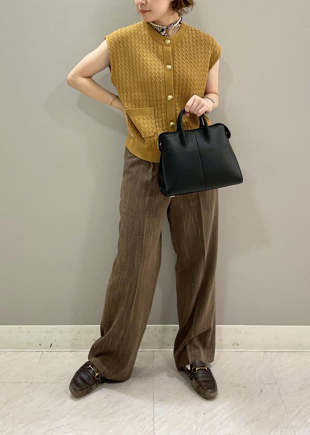 イエロー系のベスト、ブラック系のトートバッグ、ブラウン系のその他パンツを着用したレディースの夏コーディネートの3枚目の写真