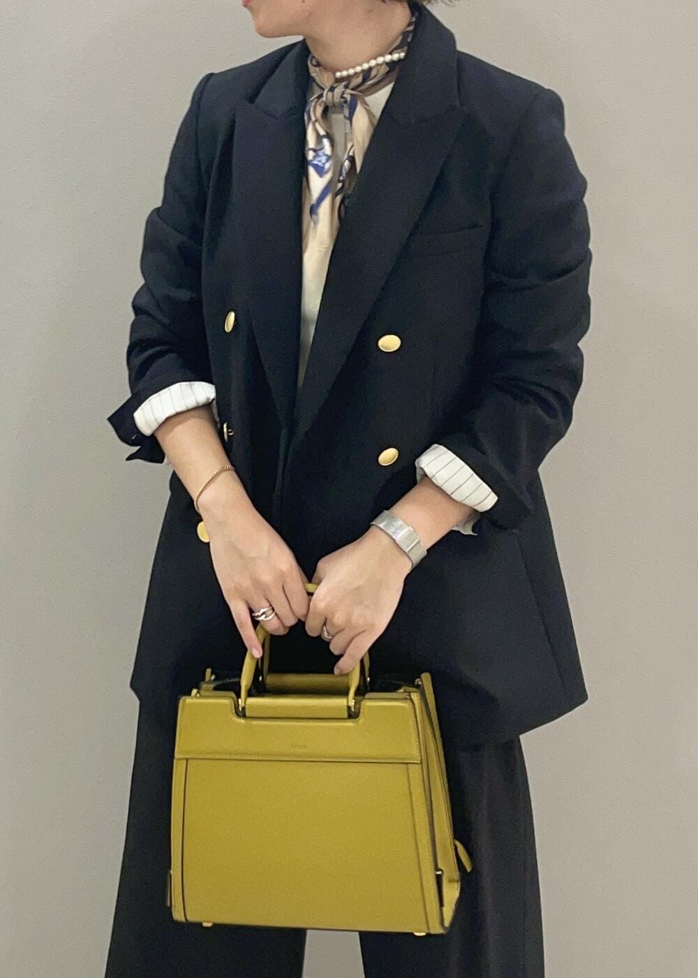 ブルー系のテーラードジャケット、イエロー系のハンドバッグ、ブラック系のブーツを着用したレディースの秋コーディネートの5枚目の写真